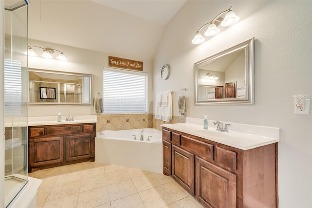 bathroom with a bathtub, vanity, vaulted ceiling, and tile patterned flooring