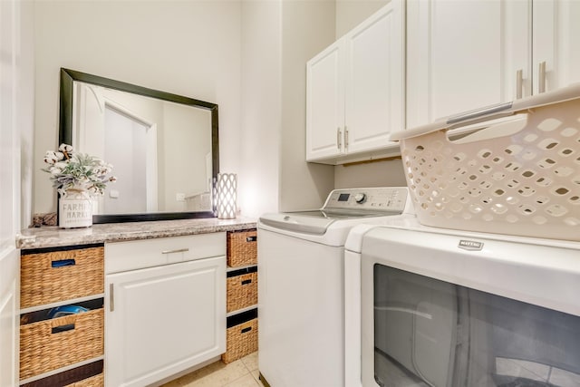 washroom featuring washer and dryer, light tile patterned floors, and cabinets