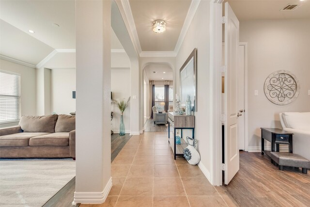 hallway with light tile patterned flooring, crown molding, and vaulted ceiling