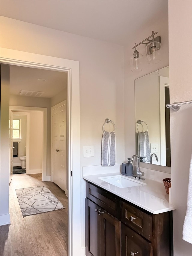 bathroom featuring vanity, hardwood / wood-style flooring, and toilet