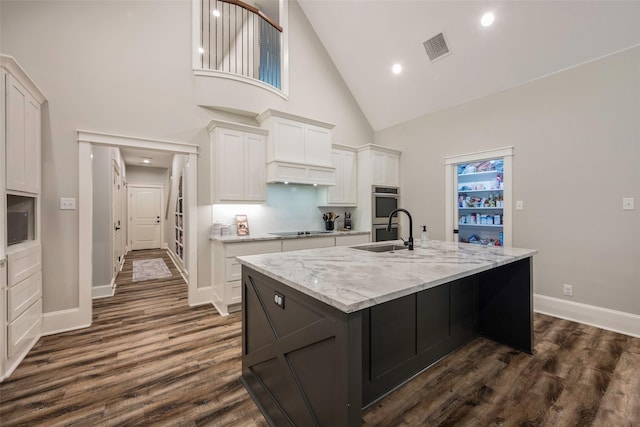 kitchen with sink, white cabinets, a kitchen island with sink, black electric stovetop, and dark wood-type flooring