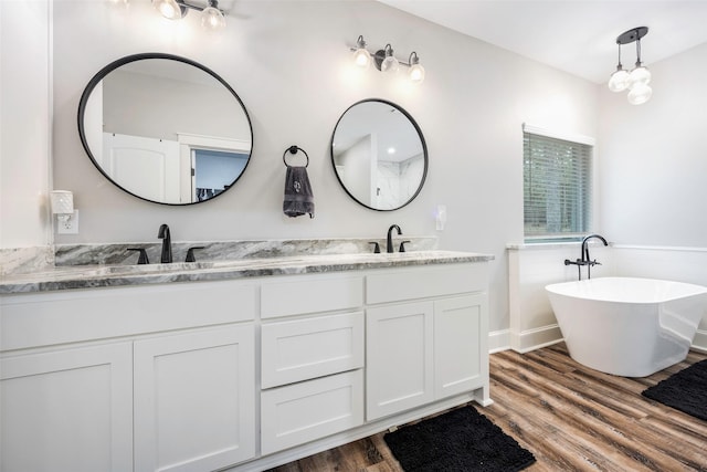 bathroom with wood-type flooring, vanity, and a tub to relax in