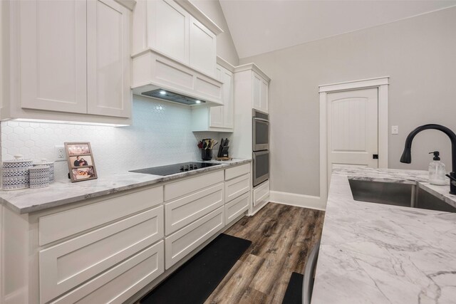 kitchen with tasteful backsplash, white cabinetry, sink, stainless steel double oven, and black electric cooktop