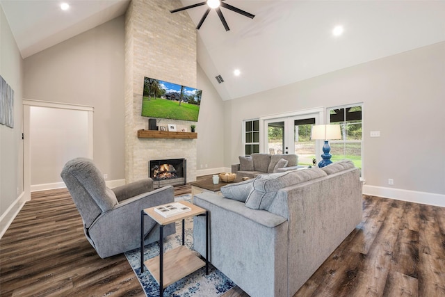 living room with dark hardwood / wood-style flooring, a stone fireplace, high vaulted ceiling, and french doors