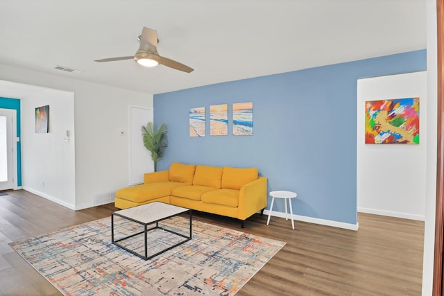 living room featuring dark wood-type flooring and ceiling fan