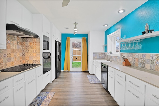 kitchen with white cabinets, sink, light hardwood / wood-style flooring, and black appliances