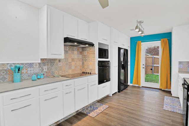 kitchen with white cabinetry, exhaust hood, decorative backsplash, and black appliances