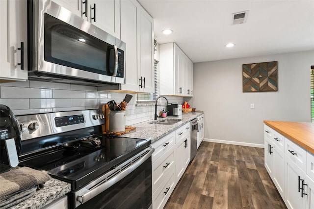 kitchen featuring white cabinets, dark hardwood / wood-style floors, appliances with stainless steel finishes, tasteful backsplash, and butcher block countertops