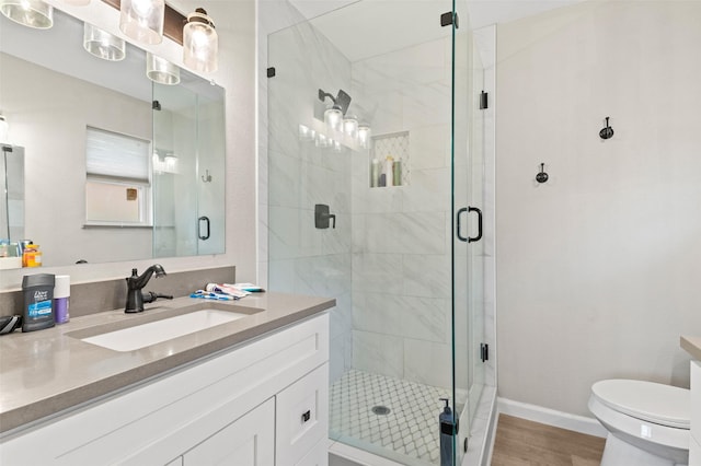 bathroom with toilet, vanity, a shower with door, and hardwood / wood-style flooring