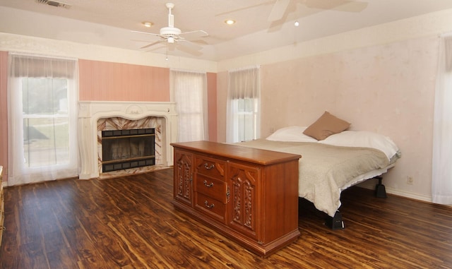 bedroom with ceiling fan, dark hardwood / wood-style floors, and a fireplace