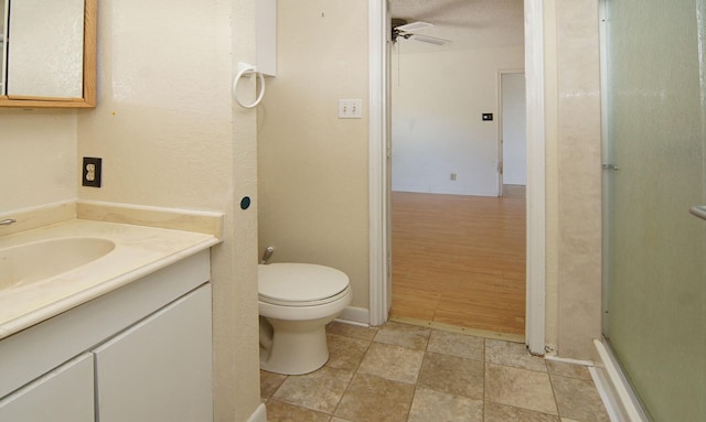 bathroom with vanity, ceiling fan, toilet, a textured ceiling, and an enclosed shower