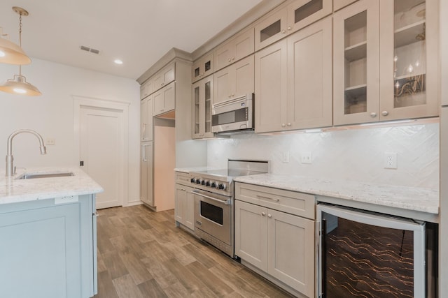 kitchen with tasteful backsplash, stainless steel appliances, beverage cooler, sink, and pendant lighting