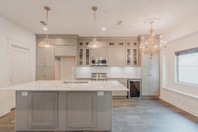 kitchen featuring wine cooler, light stone counters, sink, and decorative light fixtures