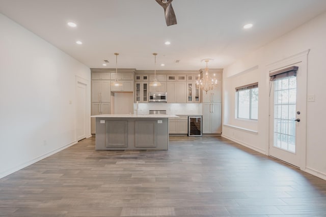 kitchen featuring wine cooler, a kitchen island with sink, hardwood / wood-style floors, and pendant lighting