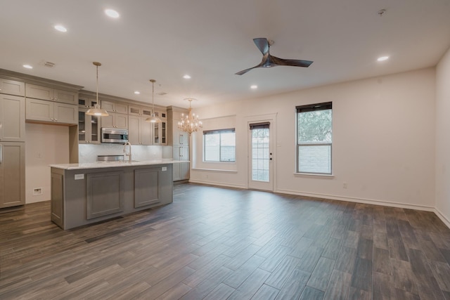 kitchen with ceiling fan with notable chandelier, sink, dark hardwood / wood-style floors, an island with sink, and decorative light fixtures