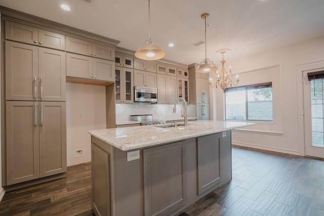 kitchen featuring light stone countertops, sink, hanging light fixtures, and a kitchen island with sink