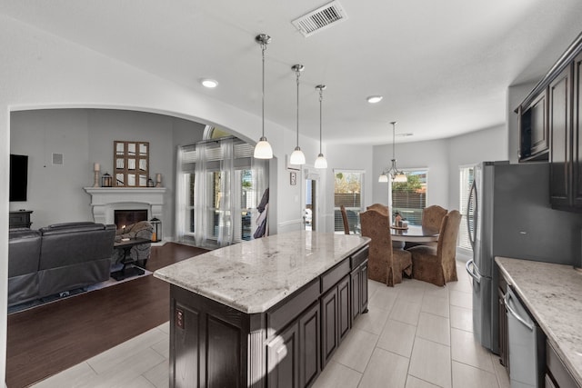 kitchen featuring appliances with stainless steel finishes, a center island, pendant lighting, and light stone counters