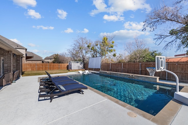 view of pool with a diving board, a patio area, and a storage shed