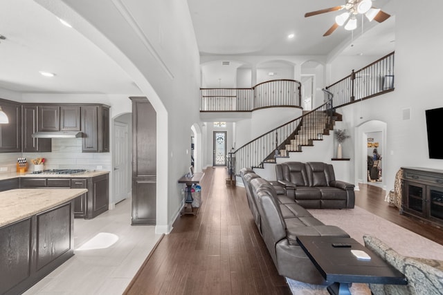 living room featuring light hardwood / wood-style floors, ceiling fan, and a high ceiling