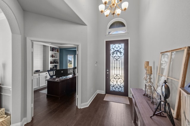 entrance foyer featuring dark wood-type flooring, a notable chandelier, and a towering ceiling