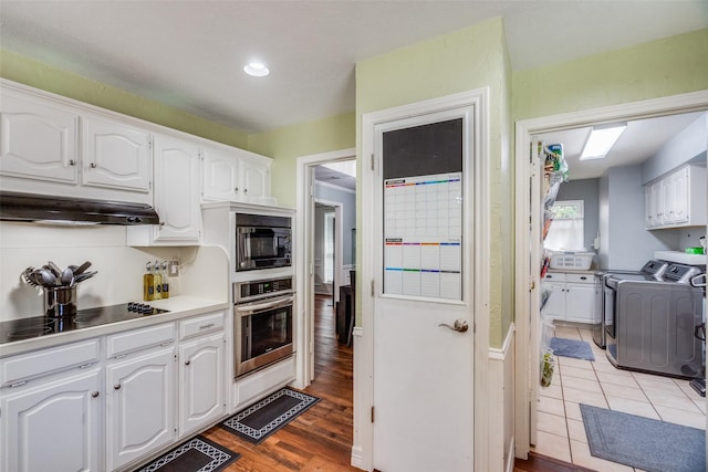 kitchen with cooktop, black microwave, oven, washing machine and dryer, and white cabinetry