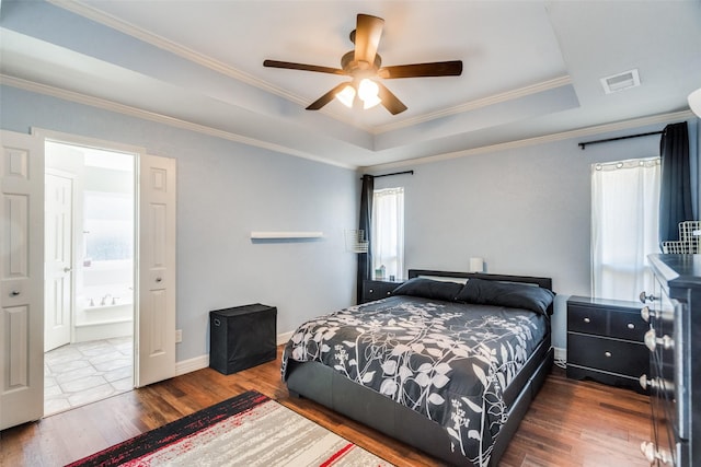 bedroom with connected bathroom, ceiling fan, a tray ceiling, hardwood / wood-style flooring, and ornamental molding