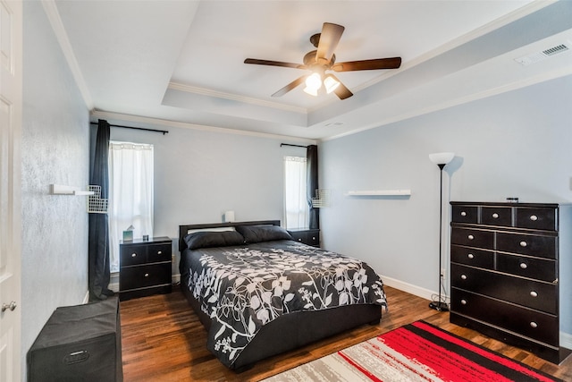 bedroom featuring a raised ceiling, ceiling fan, dark hardwood / wood-style flooring, and crown molding