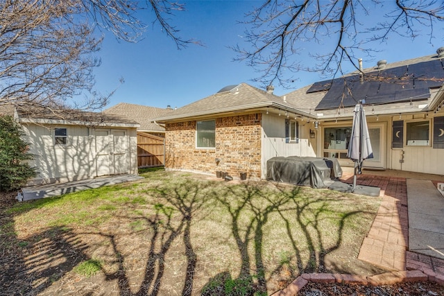 rear view of house featuring solar panels, a yard, a shed, and a patio