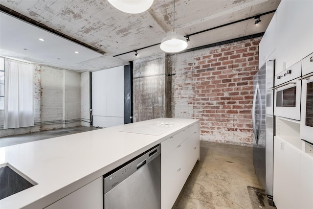 kitchen featuring stainless steel dishwasher, white cabinetry, rail lighting, and brick wall