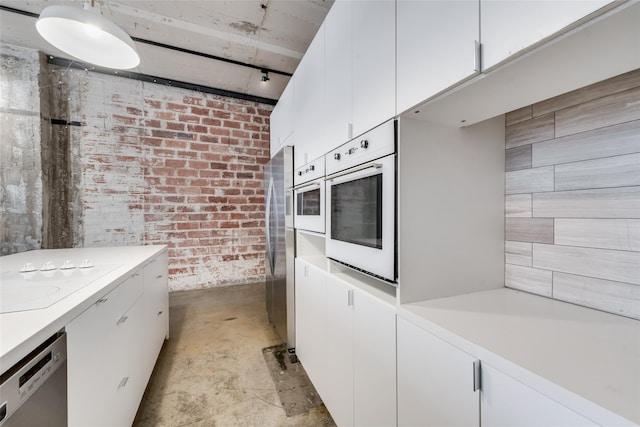 kitchen with white cabinets, stainless steel appliances, and brick wall