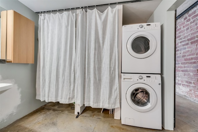 washroom with stacked washer / dryer and brick wall