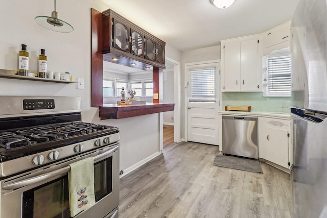 kitchen with tasteful backsplash, white cabinets, stainless steel appliances, and light wood-type flooring