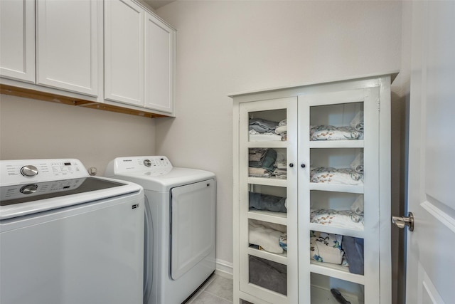 washroom featuring light tile patterned flooring, cabinets, and washing machine and clothes dryer