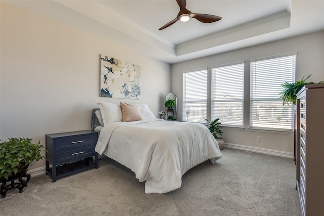 bedroom featuring light colored carpet, a raised ceiling, ceiling fan, and ornamental molding