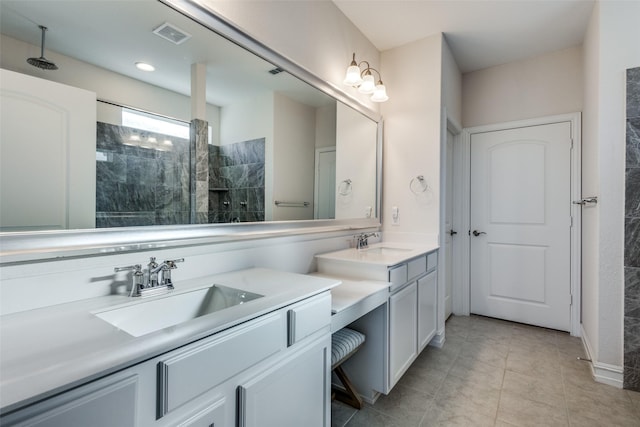 bathroom with a tile shower, vanity, and tile patterned floors