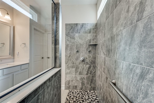 bathroom with tile patterned floors, vanity, and a tile shower