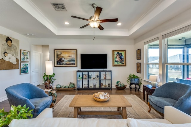 living room with a raised ceiling, ceiling fan, crown molding, and hardwood / wood-style flooring