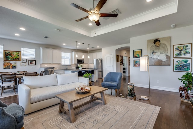 living room with a tray ceiling, ceiling fan, light hardwood / wood-style flooring, and crown molding