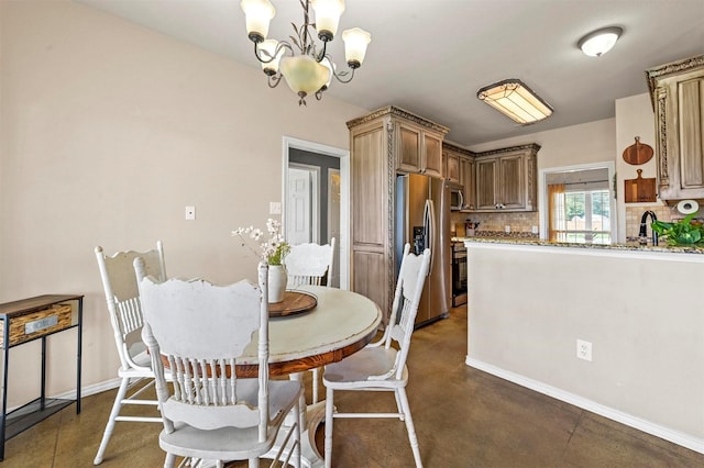 dining space featuring a notable chandelier, concrete floors, and baseboards