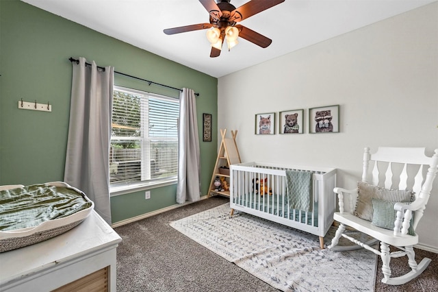 bedroom featuring a crib, carpet flooring, a ceiling fan, and baseboards