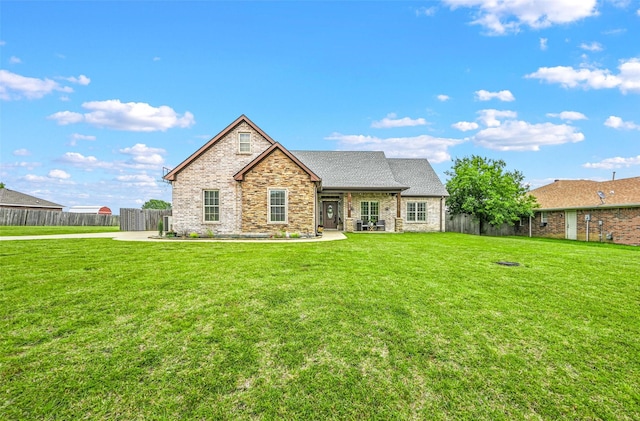 rear view of property featuring a yard, stone siding, and fence