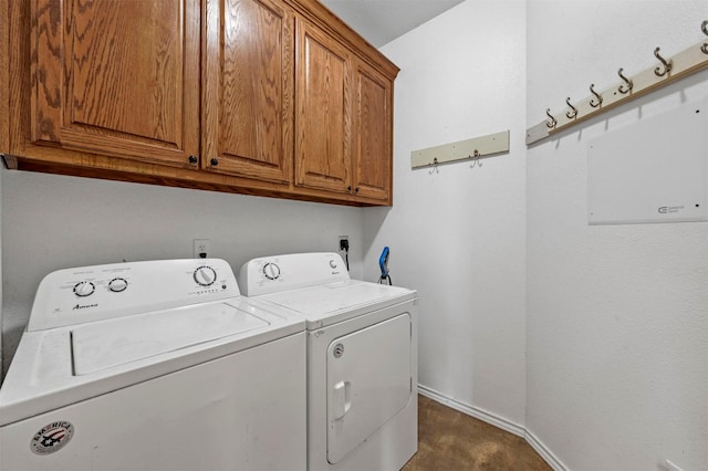 clothes washing area featuring baseboards, cabinet space, and washing machine and dryer