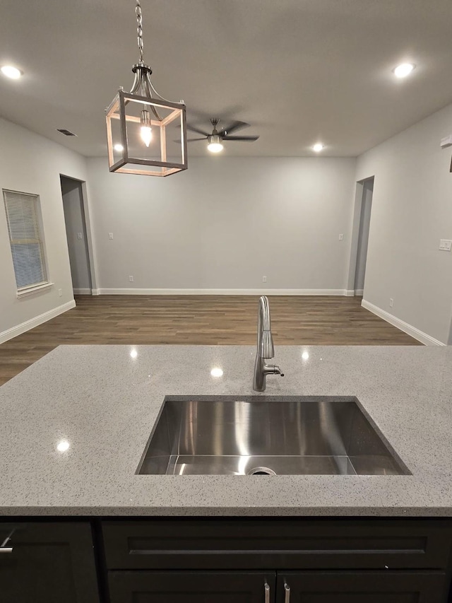 kitchen featuring pendant lighting, sink, ceiling fan, dark hardwood / wood-style floors, and light stone countertops