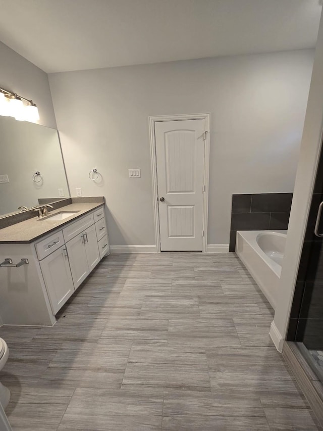 bathroom featuring toilet, vanity, a tub to relax in, and tile patterned floors