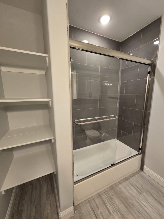 bathroom with hardwood / wood-style floors and enclosed tub / shower combo