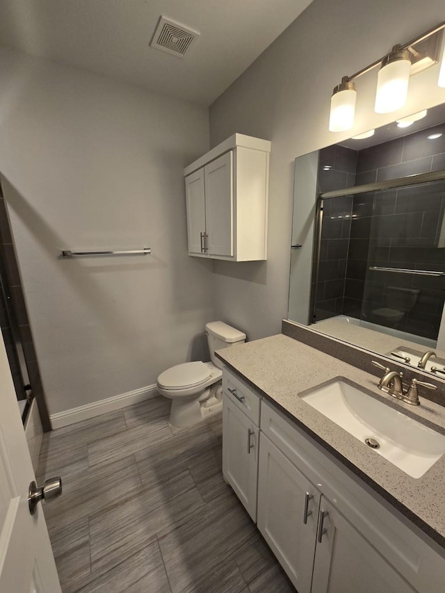 bathroom with vanity, a shower with shower door, and toilet