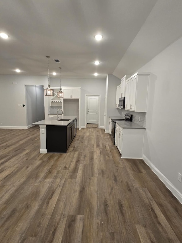 kitchen featuring black range with electric stovetop, decorative backsplash, pendant lighting, a kitchen island with sink, and white cabinets