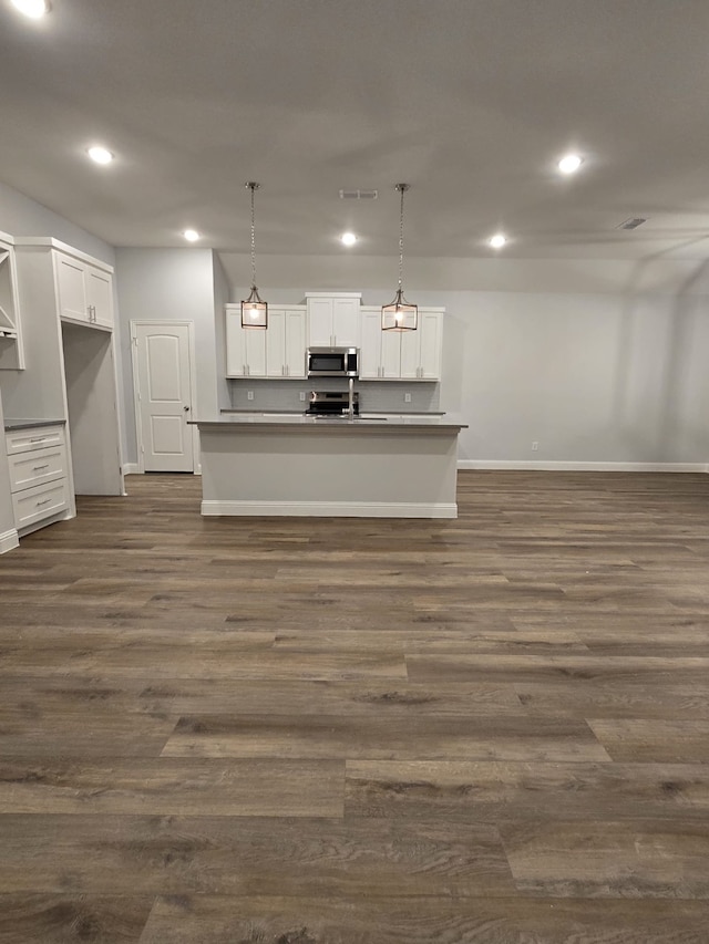 interior space featuring dark hardwood / wood-style flooring, white cabinetry, stainless steel appliances, and hanging light fixtures