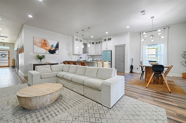 living room with a chandelier, sink, and light hardwood / wood-style flooring