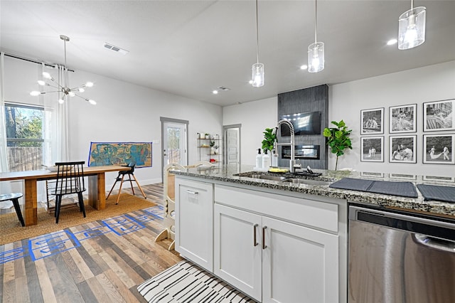 kitchen featuring white cabinets, sink, stainless steel dishwasher, light stone countertops, and a notable chandelier